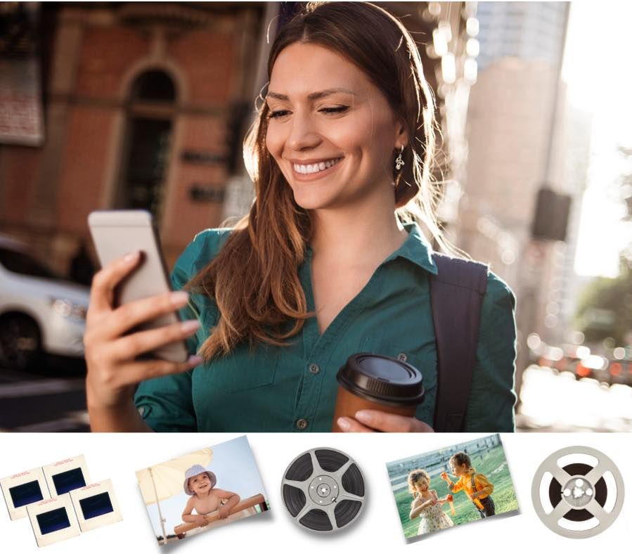 A smiling woman looking at digitized family photos on her smartphone